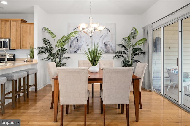 dining space with light hardwood / wood-style floors and a chandelier