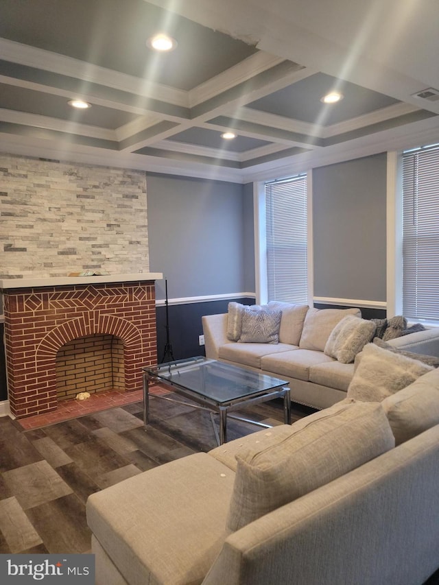 living room featuring ornamental molding, a fireplace, coffered ceiling, and dark wood-type flooring