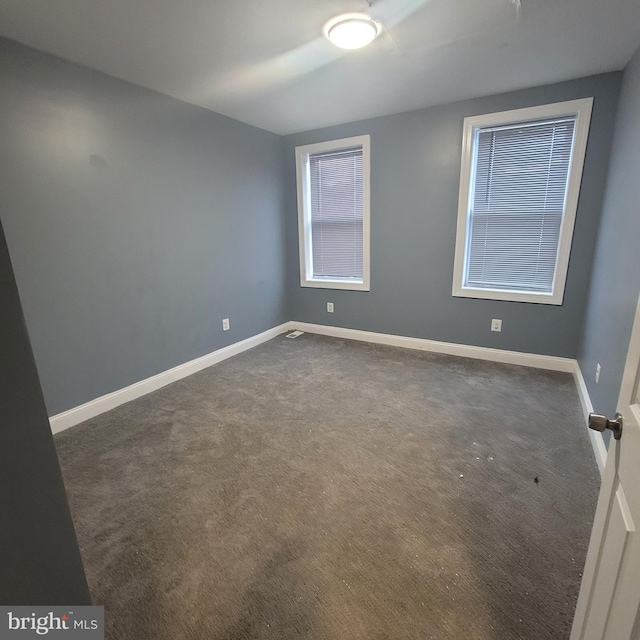 unfurnished room featuring dark carpet