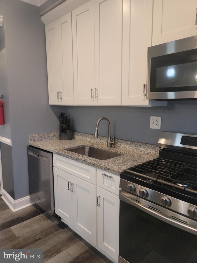 kitchen featuring dark wood-type flooring, sink, white cabinets, appliances with stainless steel finishes, and light stone countertops