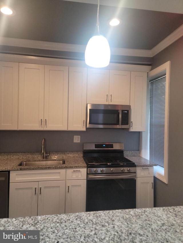 kitchen with light stone countertops, white cabinets, appliances with stainless steel finishes, and sink