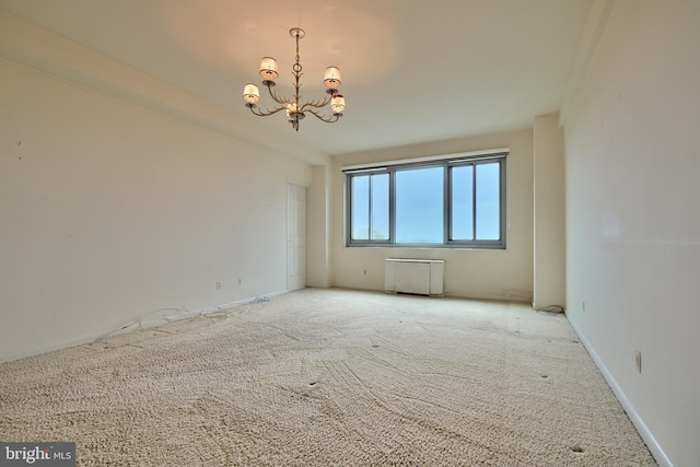 spare room with light colored carpet and a chandelier