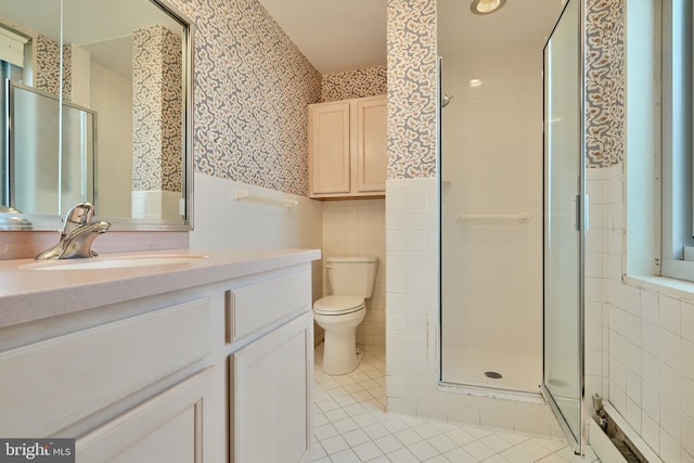 bathroom with vanity, tile patterned flooring, toilet, tile walls, and a shower with shower door