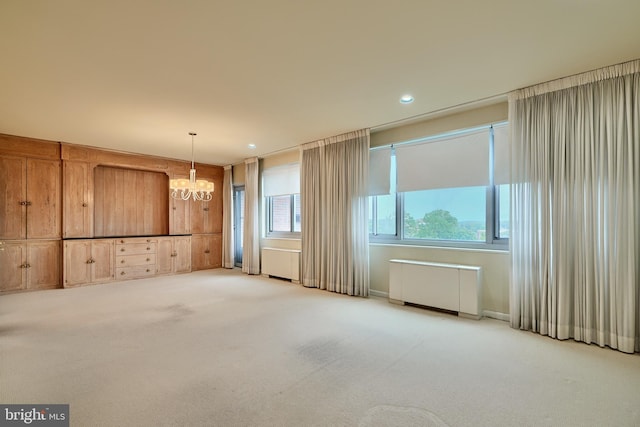 carpeted empty room with an inviting chandelier