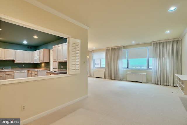 kitchen with white appliances, radiator heating unit, ornamental molding, light colored carpet, and white cabinetry