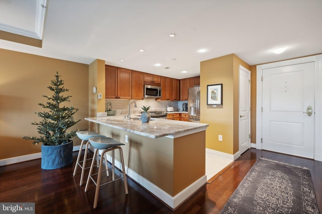 kitchen featuring a breakfast bar, dark hardwood / wood-style flooring, kitchen peninsula, and appliances with stainless steel finishes