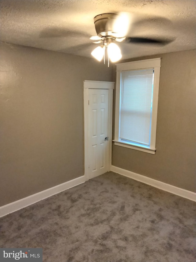 carpeted empty room with ceiling fan and a textured ceiling