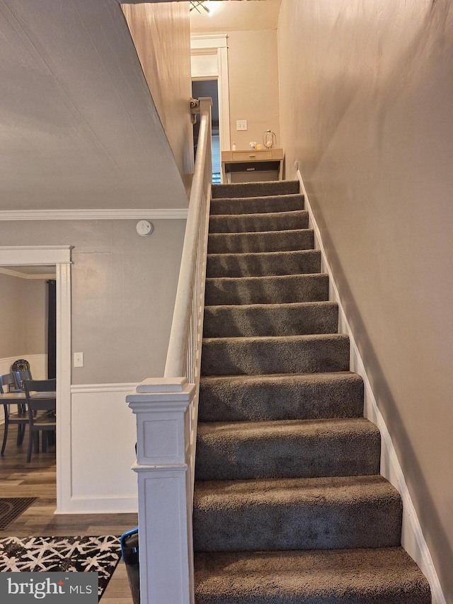 staircase with ornamental molding and hardwood / wood-style floors