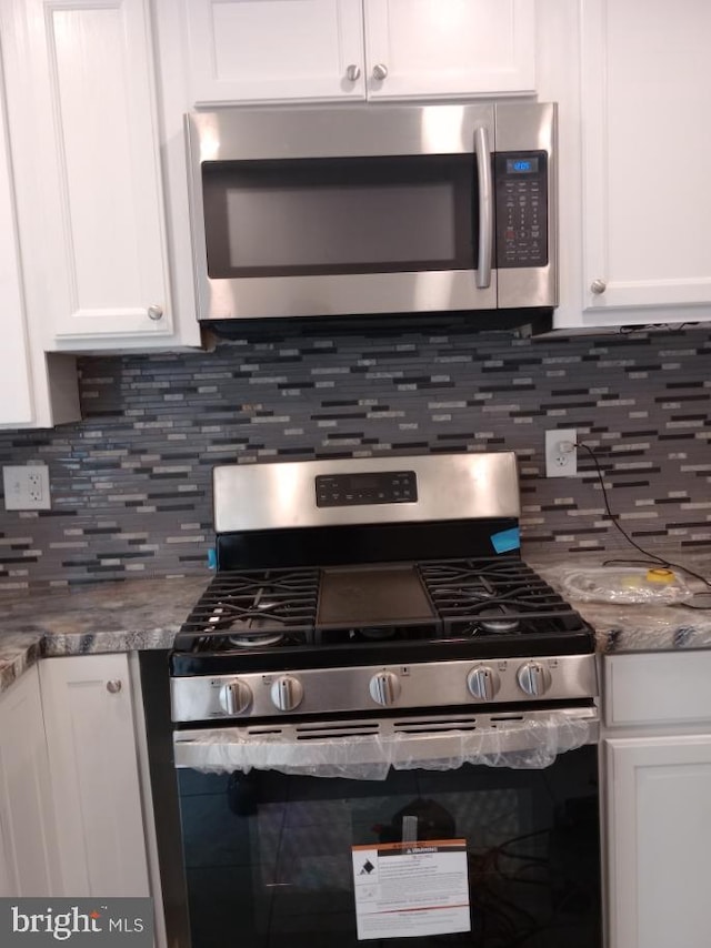 kitchen with decorative backsplash, stainless steel appliances, white cabinetry, and stone countertops