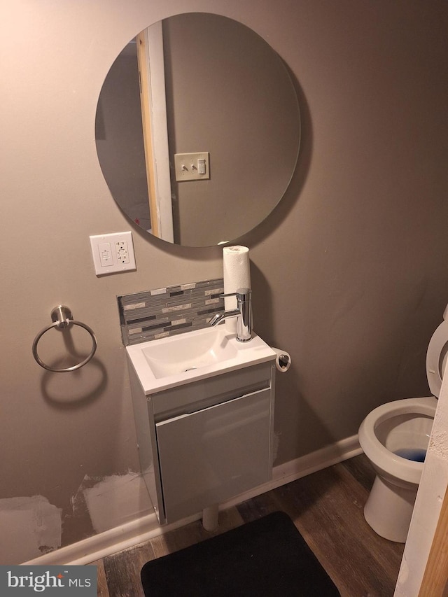 bathroom with vanity, hardwood / wood-style floors, toilet, and decorative backsplash