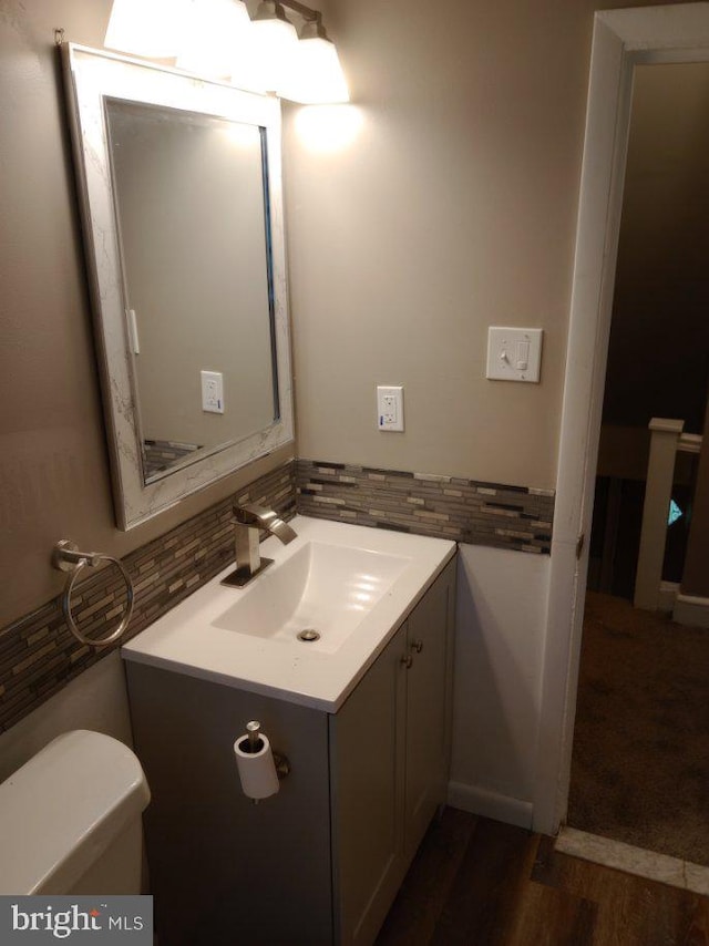 bathroom with backsplash, vanity, toilet, and hardwood / wood-style flooring