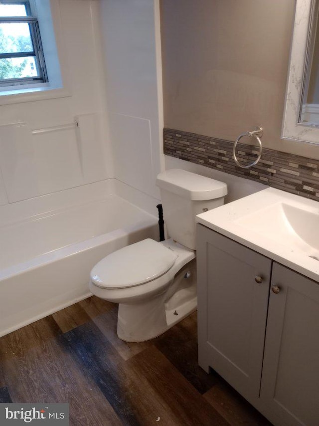 full bathroom featuring vanity, shower / bath combination, hardwood / wood-style flooring, toilet, and decorative backsplash