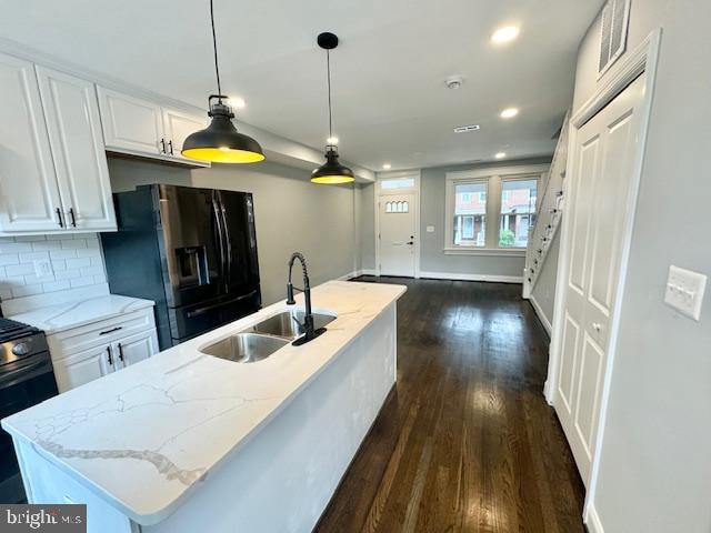 kitchen featuring sink, an island with sink, white cabinets, dark hardwood / wood-style floors, and black fridge with ice dispenser