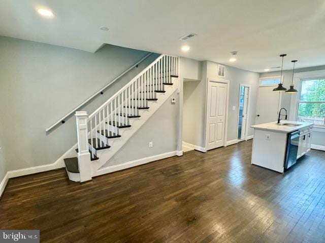 interior space featuring white cabinetry, stainless steel dishwasher, dark hardwood / wood-style floors, sink, and decorative light fixtures