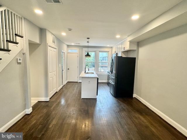 kitchen with white cabinets, decorative light fixtures, dark wood-type flooring, and black fridge