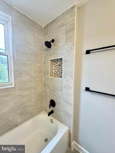 bathroom with a wealth of natural light and tiled shower / bath combo