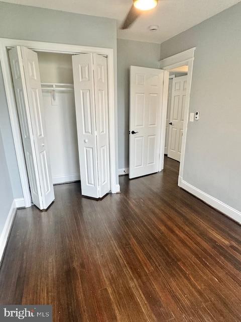 unfurnished bedroom featuring ceiling fan, a closet, and dark hardwood / wood-style flooring