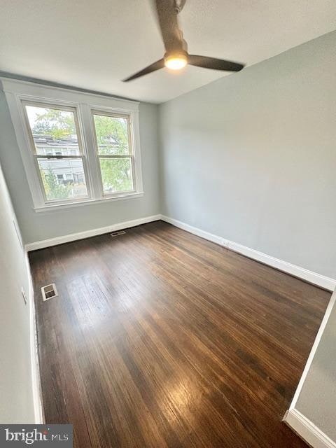 spare room featuring dark wood-type flooring and ceiling fan