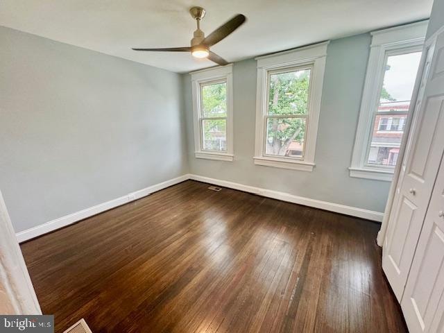 empty room featuring dark wood-type flooring and ceiling fan