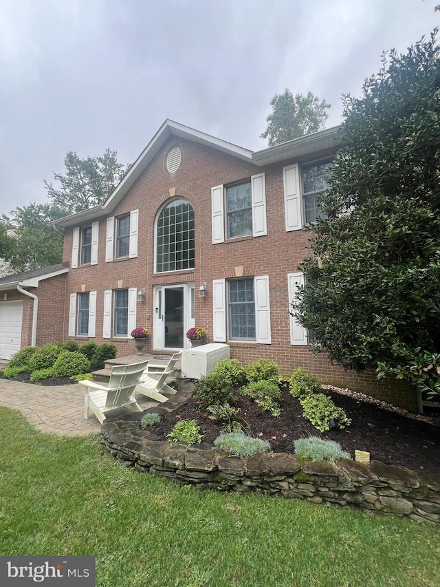 colonial home with a garage and a front lawn