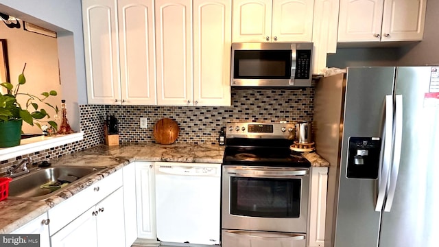 kitchen featuring white cabinetry, appliances with stainless steel finishes, light stone counters, and sink