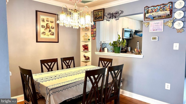 dining area featuring ornamental molding, wood-type flooring, and a chandelier