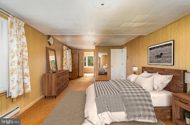 bedroom featuring wooden walls, light carpet, and a baseboard radiator