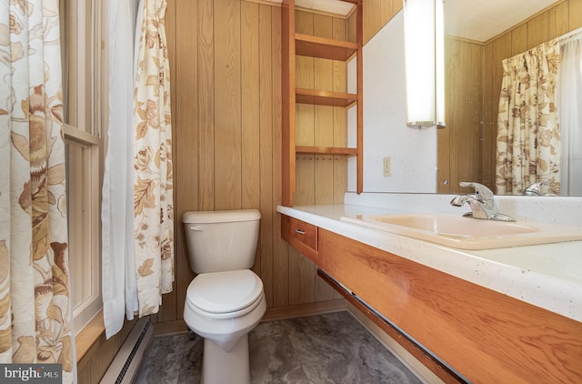 bathroom with vanity, wood walls, toilet, and a baseboard heating unit