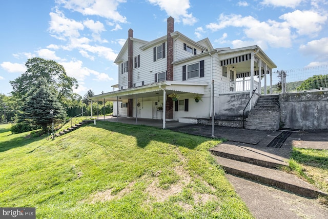 rear view of property featuring a yard and covered porch