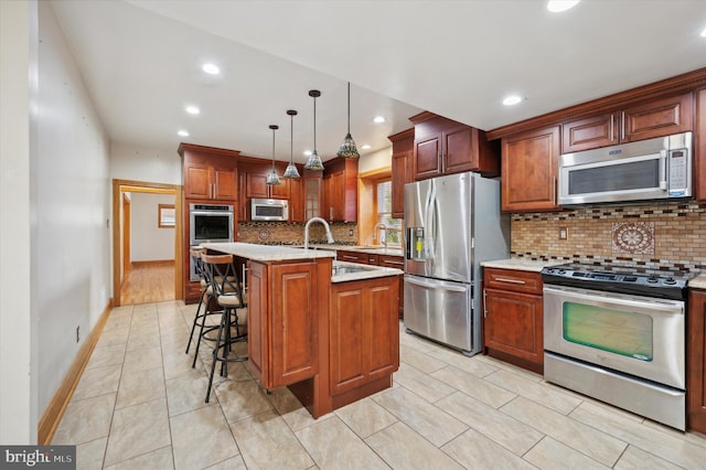 kitchen featuring pendant lighting, decorative backsplash, appliances with stainless steel finishes, and an island with sink