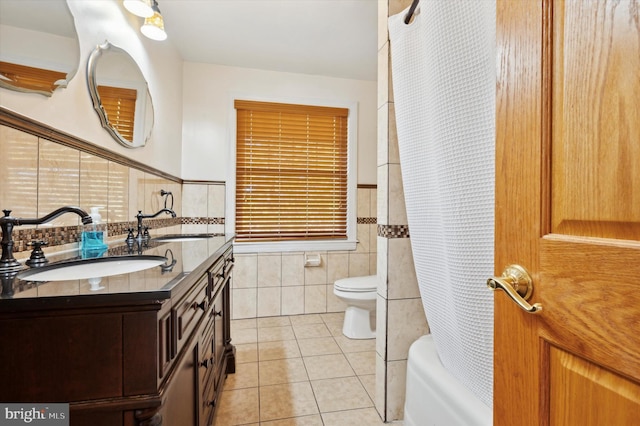 full bathroom featuring shower / bathtub combination with curtain, vanity, tile patterned floors, toilet, and tile walls