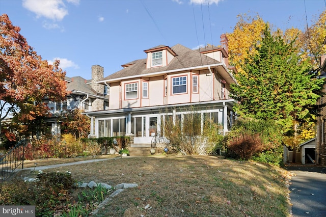 view of front of house with a sunroom and a front yard