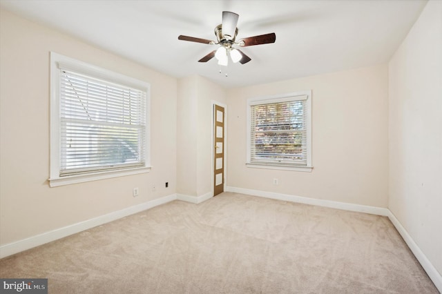 unfurnished room with ceiling fan, light colored carpet, and a healthy amount of sunlight