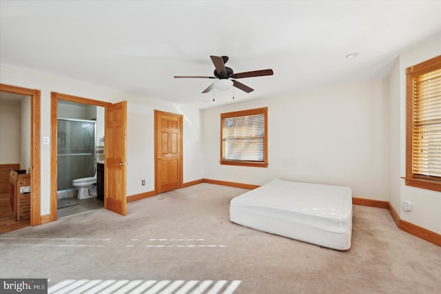 unfurnished bedroom featuring ceiling fan, ensuite bath, and light carpet