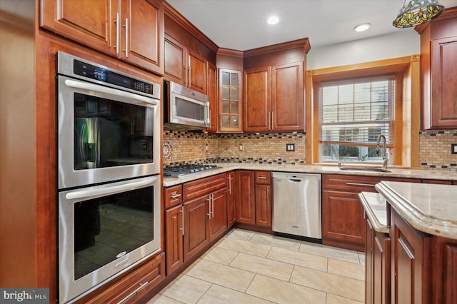 kitchen featuring light stone counters, light tile patterned flooring, stainless steel appliances, backsplash, and sink