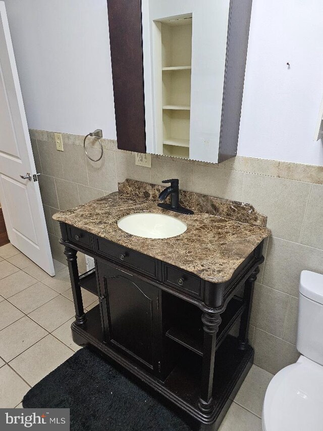 bathroom with vanity, tile walls, tile patterned flooring, and toilet