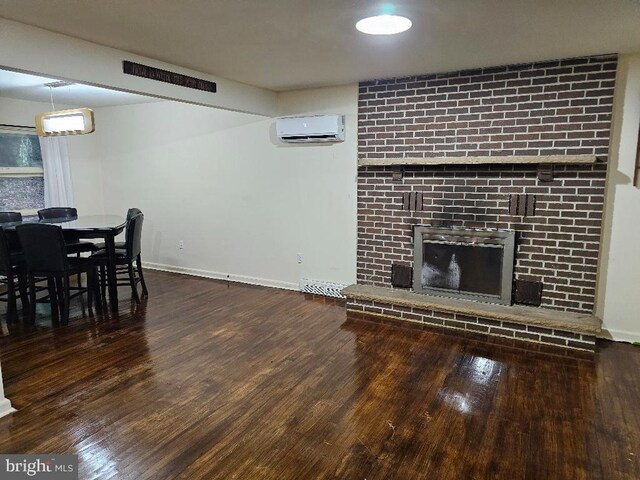 living room with a brick fireplace, dark hardwood / wood-style floors, and a wall mounted air conditioner