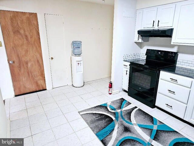 kitchen featuring black electric range oven, light tile patterned floors, and white cabinets