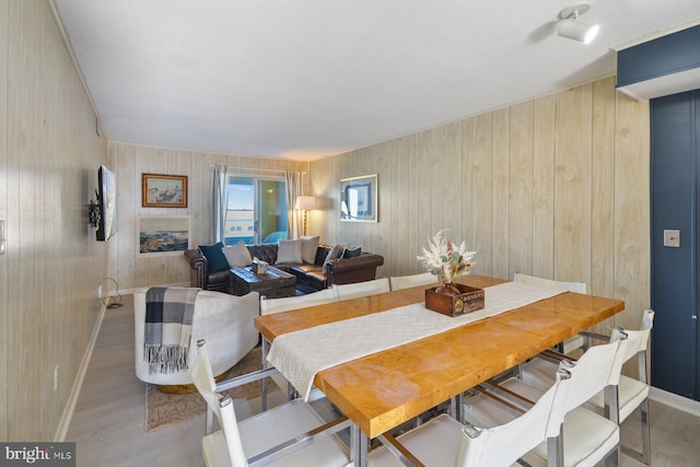 dining space with light wood-type flooring and wood walls