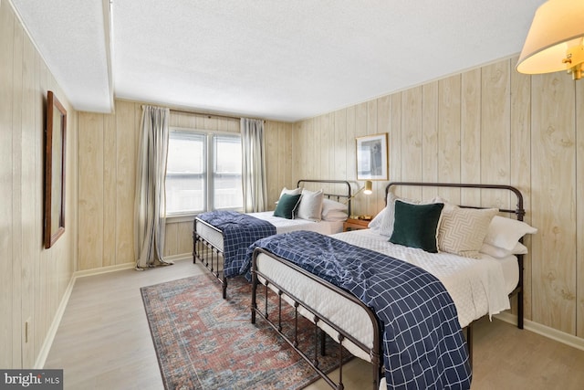 bedroom featuring a textured ceiling, wood walls, and hardwood / wood-style floors