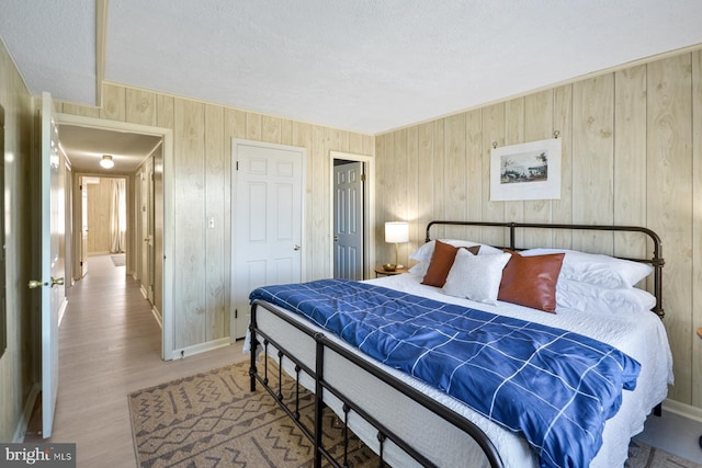 bedroom with wood-type flooring, a textured ceiling, wooden walls, and a closet