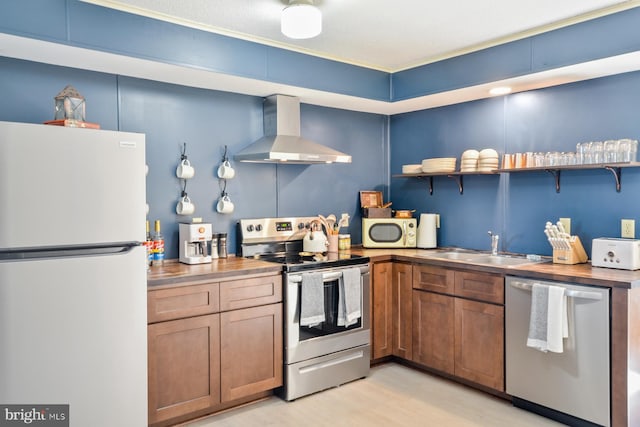 kitchen with light wood-type flooring, wood counters, sink, wall chimney exhaust hood, and stainless steel appliances