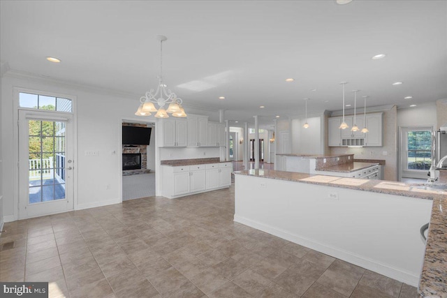 kitchen featuring an inviting chandelier, a kitchen island, hanging light fixtures, and white cabinetry