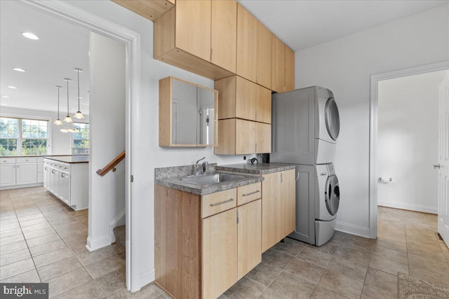 kitchen featuring a chandelier, sink, stacked washing maching and dryer, light tile patterned floors, and light brown cabinetry