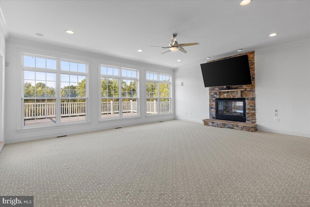 unfurnished living room with ceiling fan, a fireplace, crown molding, and carpet