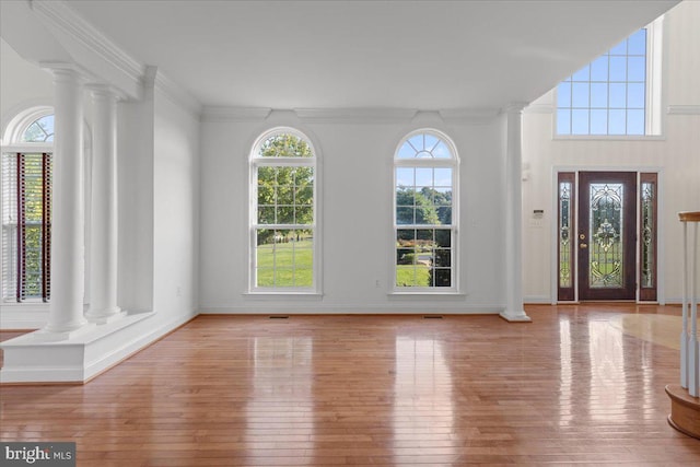 entryway featuring light hardwood / wood-style flooring, ornamental molding, and ornate columns