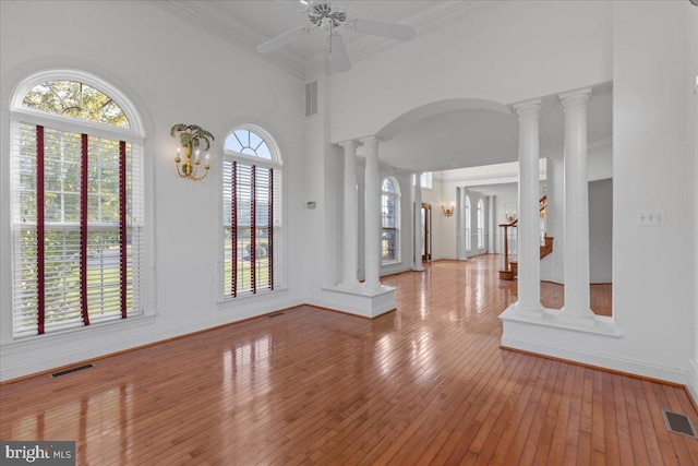 entrance foyer featuring ceiling fan, hardwood / wood-style flooring, crown molding, and ornate columns