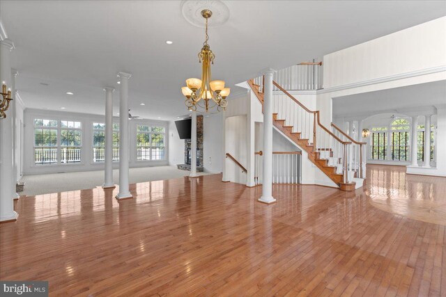 spare room with decorative columns, light hardwood / wood-style floors, and an inviting chandelier