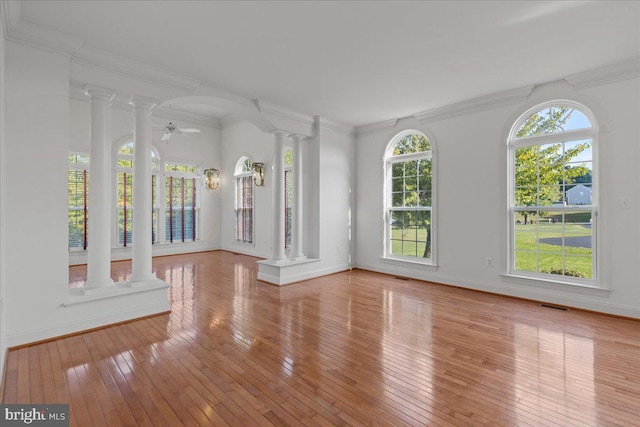 unfurnished room with ceiling fan, ornamental molding, light wood-type flooring, and ornate columns