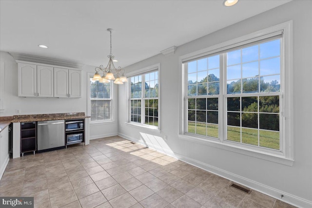 kitchen with a wealth of natural light, a notable chandelier, stainless steel appliances, and white cabinetry